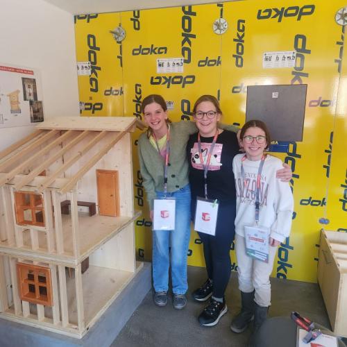 Schülerinnen stecken ein Holzhaus zusammen