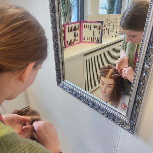 Schülerin flechtet Puppe die Haare