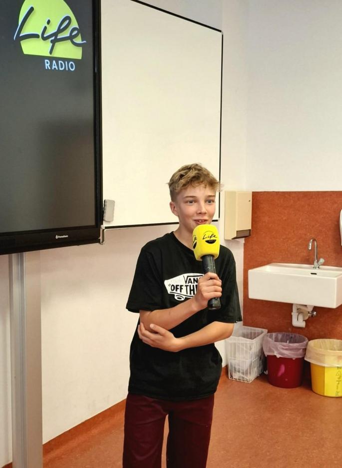 Kind mit Mikrofon in einer Schulklasse